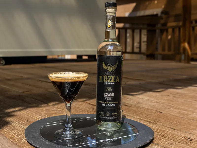 Espresso Martini dans un verre à martini à côté d'une bouteille de Kuzca Espadín