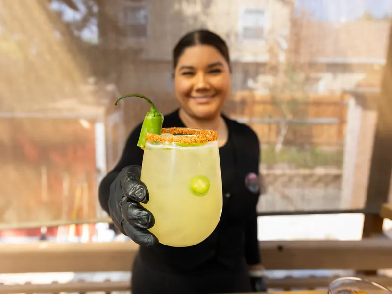 Mezcalita Piquilina au piment serrano, verre givré, servie par une barmaid