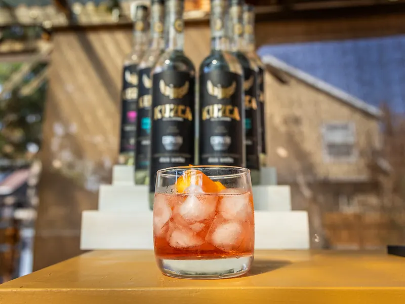 Old Fashioned avec glace et zeste d'orange devant des bouteilles Kuzca